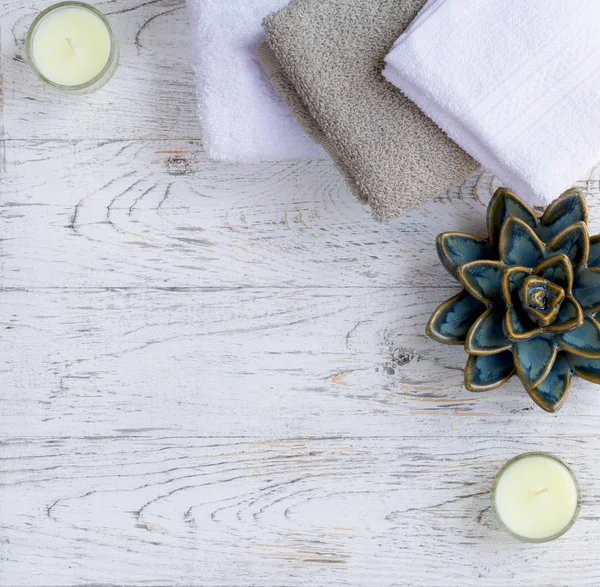Candle, towel and ceramic plant on white wooden table. Body Care concept