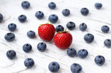 İki tatlı çilek ve böğürtlenli Beyaz ahşap zemin üzerinde.