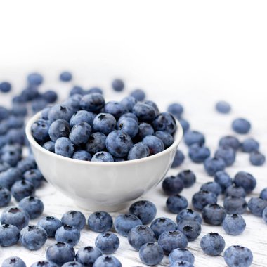 Kase Beyaz ahşap masa üzerinde olgunlaşmış bluberries.