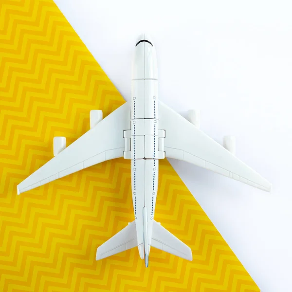 Flat lay design of travel concept with plane on yellow and white background