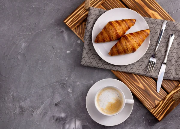 Flatlay de croissant, une tasse de café au plateau en bois avec serviette sur une table en béton gris pierre . — Photo