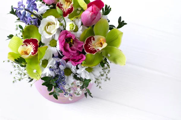 Luxury beautiful pink bouquet of various flowers in round pink box on white wooden background