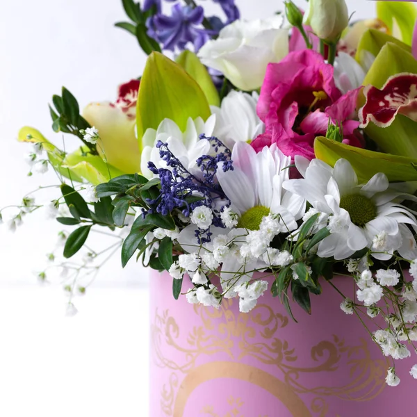 Luxury beautiful pink bouquet of various flowers in round pink box on white wooden background