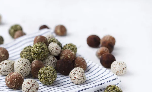 Organic energy bites with dates, pumpkin seeds, almond, walnut and sesame at the white background.