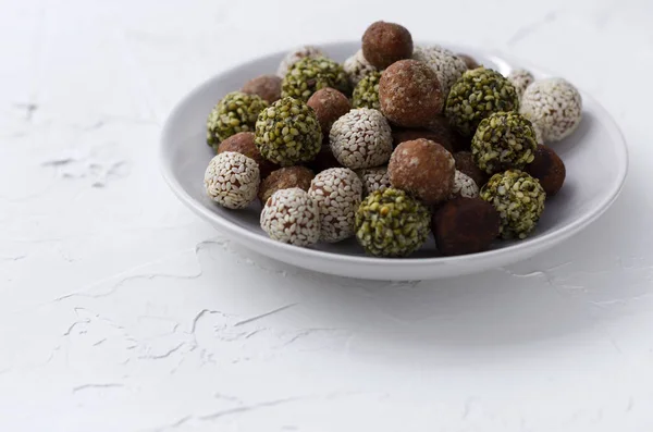 Organic energy bites with dates, pumpkin seeds, almond, walnut and sesame at the white background.