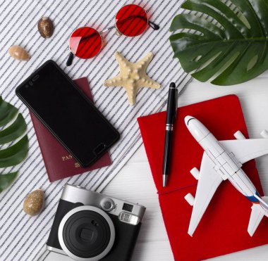 Düz yatıyordu seyahat konsepti: planlayıcı, pasaport, akıllı telefon, kamera, kalem, yıldız balık ve monstera ahşap arka plan üzerinde yaprakları