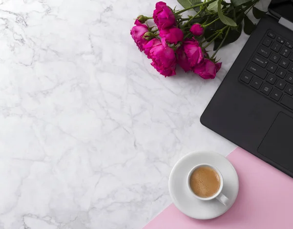 Espacio de trabajo femenino con ordenador portátil, ramo de rosas y café sobre una mesa de mármol . — Foto de Stock