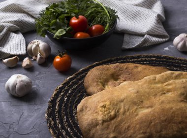 Domates, sarımsak ve maydanoz ile gri masada lezzetli taze tandır ekmek. Ulusal Gürcü mutfağı ve yemekleri. 