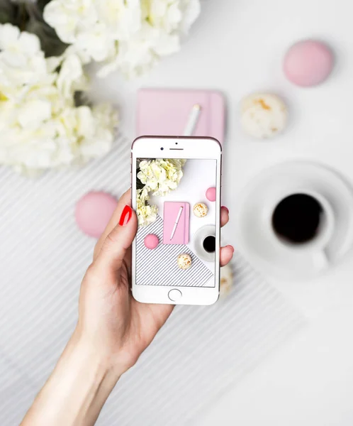 Kadın akıllı telefondan çalışma alanının fotoğrafını çekiyor. Pembe defter