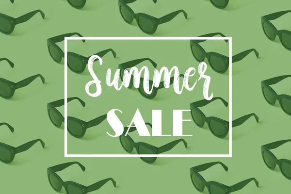 Summer sale banner with sunglasses pattern on green background.
