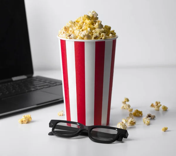Popcorn in striped red bucket, 3d glasses, and laptop playing mo — Stock Photo, Image