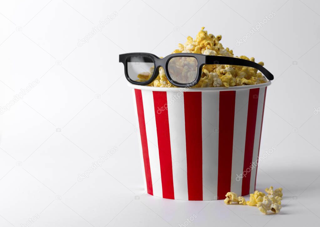 Popcorn in striped red bucket with 3d glasses at white backgroun