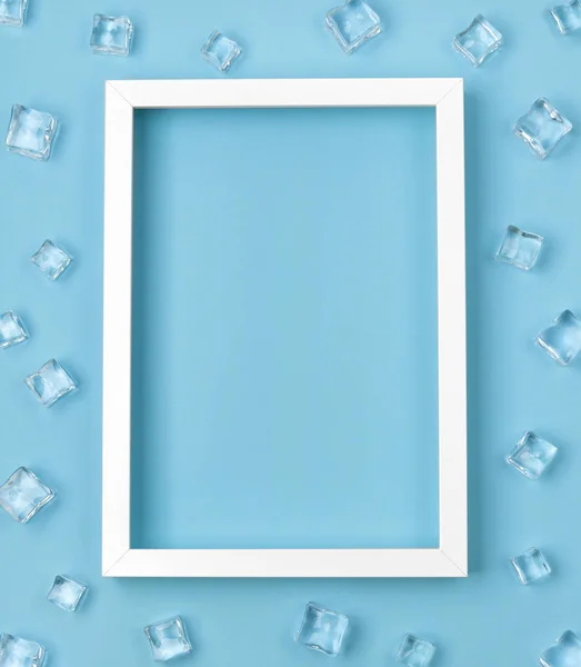 Плоский макет з білою рамкою та кубиками льоду на синьому фоні . — стокове фото