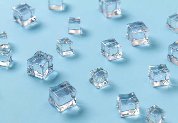 Ice cubes scattered on a light blue background. — Stock Photo, Image