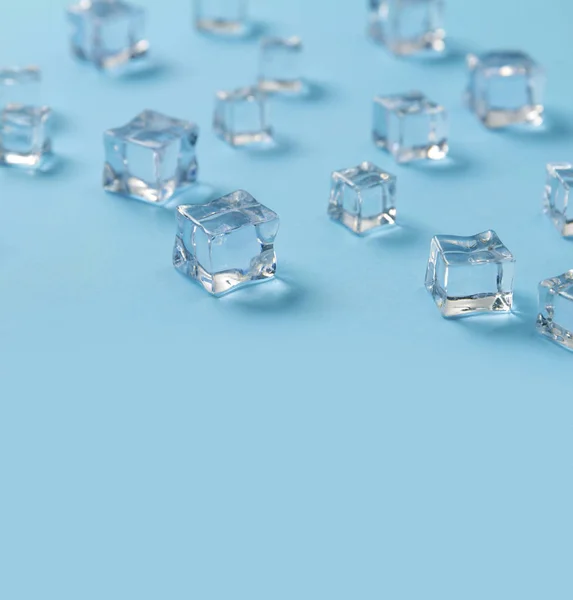 Ice cubes scattered on a light blue background. — Stock Photo, Image