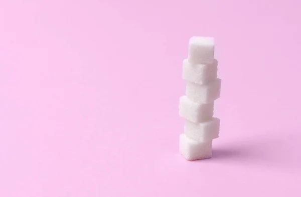 Hromádka cukrů na růžovém pozadí. — Stock fotografie