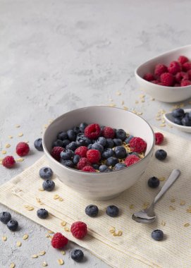 Yulaf gevreği, yaban mersini ve ahududu gri beton arka plan üzerinde.