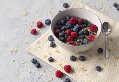 Yulaf gevreği, yaban mersini ve ahududu gri beton arka plan üzerinde.