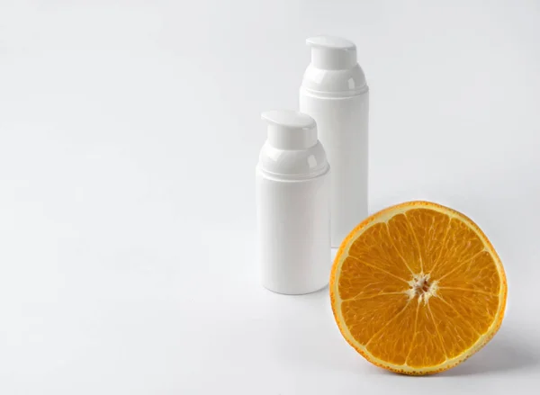 Duas garrafas de creme cosmético com laranja sobre fundo branco . — Fotografia de Stock