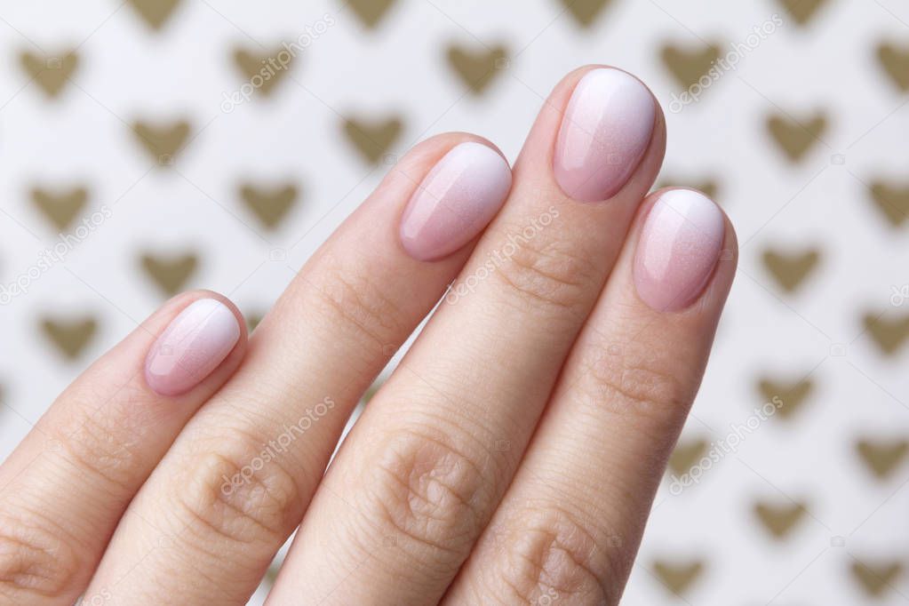Hand with manicure at the creative background with hearts. 