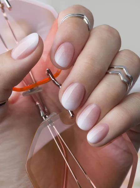 Güneş gözlüğü tutan halkalar ile güzel manikürlü el.