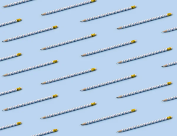 Pattern composition of blue striped pencils on pastel blue background.