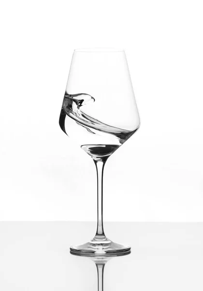 Klares Weinglas mit Wasserstoß. Bewegung gegen Weiß — Stockfoto