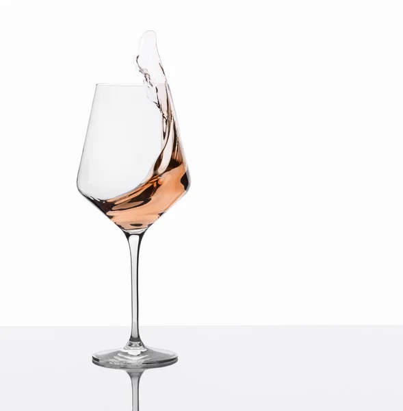 Склянка бурштинового вина з бризками на білому тлі . — стокове фото