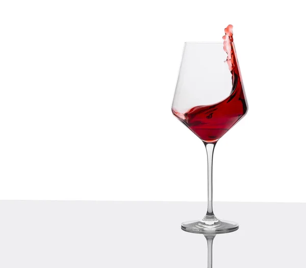 Bicchiere di vino rosso con spruzzi sul tavolo bianco . — Foto Stock