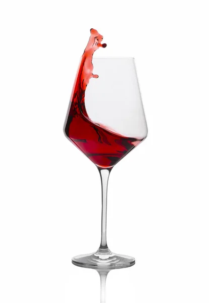 Червоне вино виливається зі склянки ізольовано на білому — стокове фото