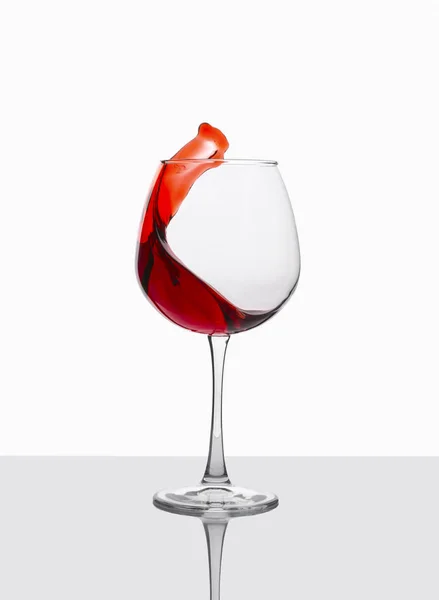 Glas Rotwein mit Spritzern auf weißem Tisch. — Stockfoto