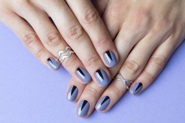 Mor arka planda yaratıcı minimal manikür ile iki kadın eller.