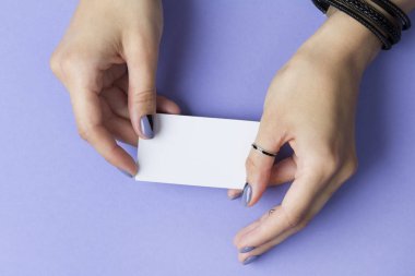 Boş bir kartviziti tutan kadın manikürlü eller