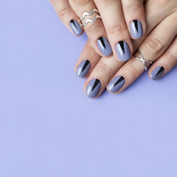 Dos manos femeninas con manicura mínima creativa en el fondo púrpura . — Foto de Stock