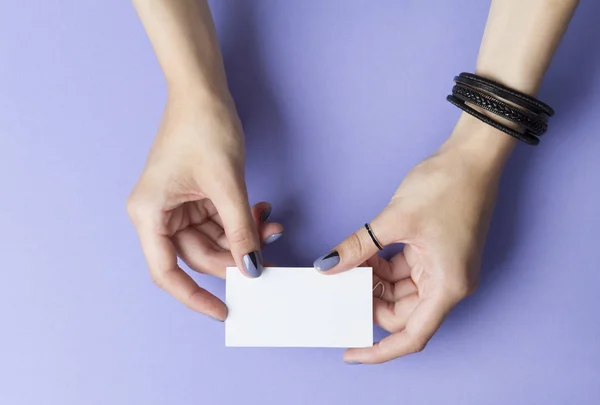 Kvinnliga manikyrerade händer som håller ett tomt visitkort — Stockfoto
