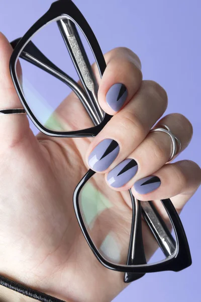 Kobieca ręka z modnym manicure trzymanie czarnych okularów — Zdjęcie stockowe