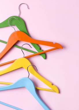 Yaratıcı düz kopya alanı minimalist tarzı ile pembe pastel arka planda çok renkli ahşap askıları yatıyordu.