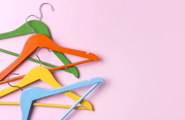 Yaratıcı düz kopya alanı minimalist tarzı ile pembe pastel arka planda çok renkli ahşap askıları yatıyordu.