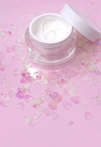 Kosmetické krémové mléko na růžovém holografickém srdci konfety třpytí pozadí s prostorem pro kopírování. — Stock fotografie