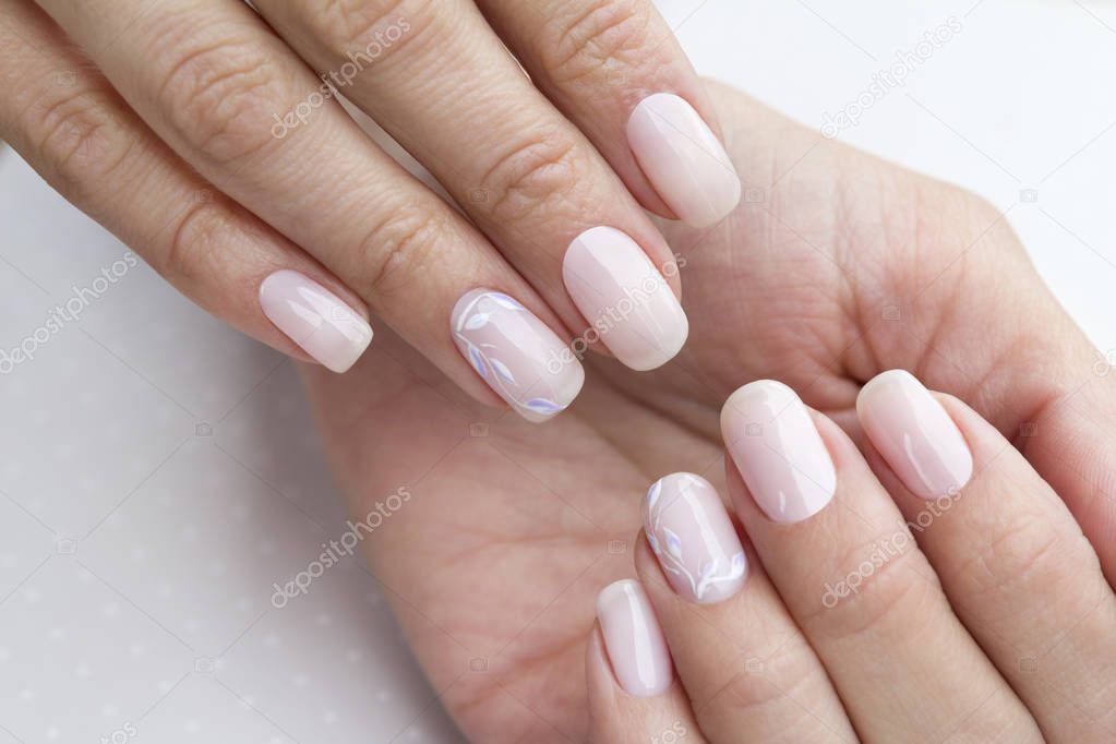 Beautiful groomed woman's hands with feminine nails on the light