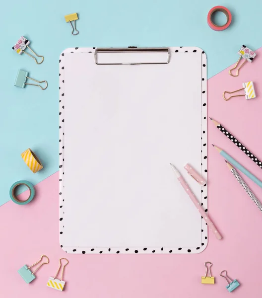 Yaratıcı pembe ve mavi arka planda pano, kalem, bağlayıcı, kalem ve koli bandı.