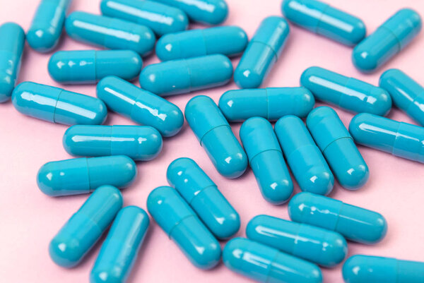 Синие таблетки на розовом фоне. Шаблон женской красоты

