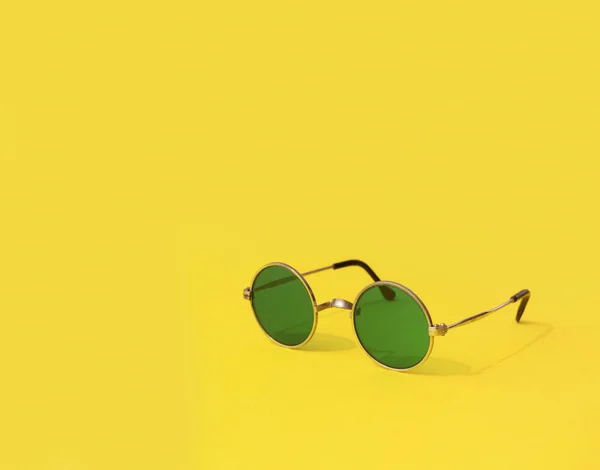 Vintage modne okrągłe zielone okulary przeciwsłoneczne na żółtym tle — Zdjęcie stockowe