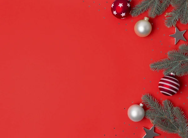 Marco de composición navideña hecho de ramas de abeto, adornos de bolas y estrellas sobre fondo rojo . — Foto de Stock