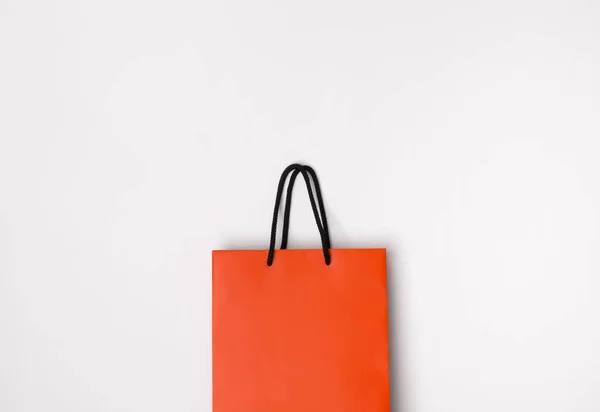 Orange paper shopping bag with black handles on the white backgr — Stock Photo, Image