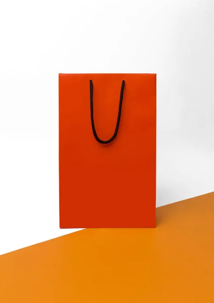 Orange paper shopping bag with black handles on the white backgr — Stock Photo, Image