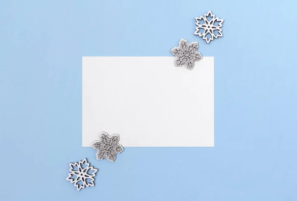 Carta de felicitación en blanco con copos de nieve de madera sobre fondo azul — Foto de Stock