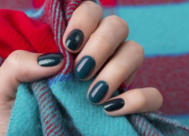 Manicured woman's hands holding warm wool turquoise fabric