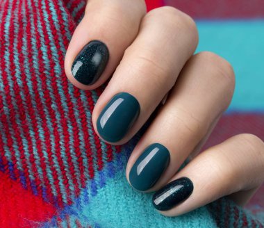 Woman's hands with turquoise glittering manicure holding warm wo