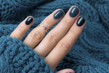 Manicured woman's hand in warm wool turquoise sweater